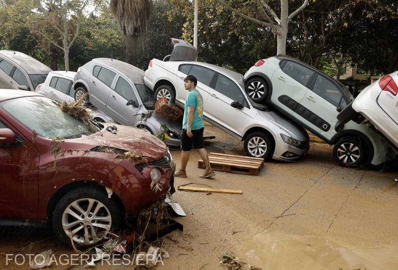 A man walks past piled-up cars following heavy rains and floods in the village of Picana, in the province of Valencia, eastern Spain, 30 October 2024.